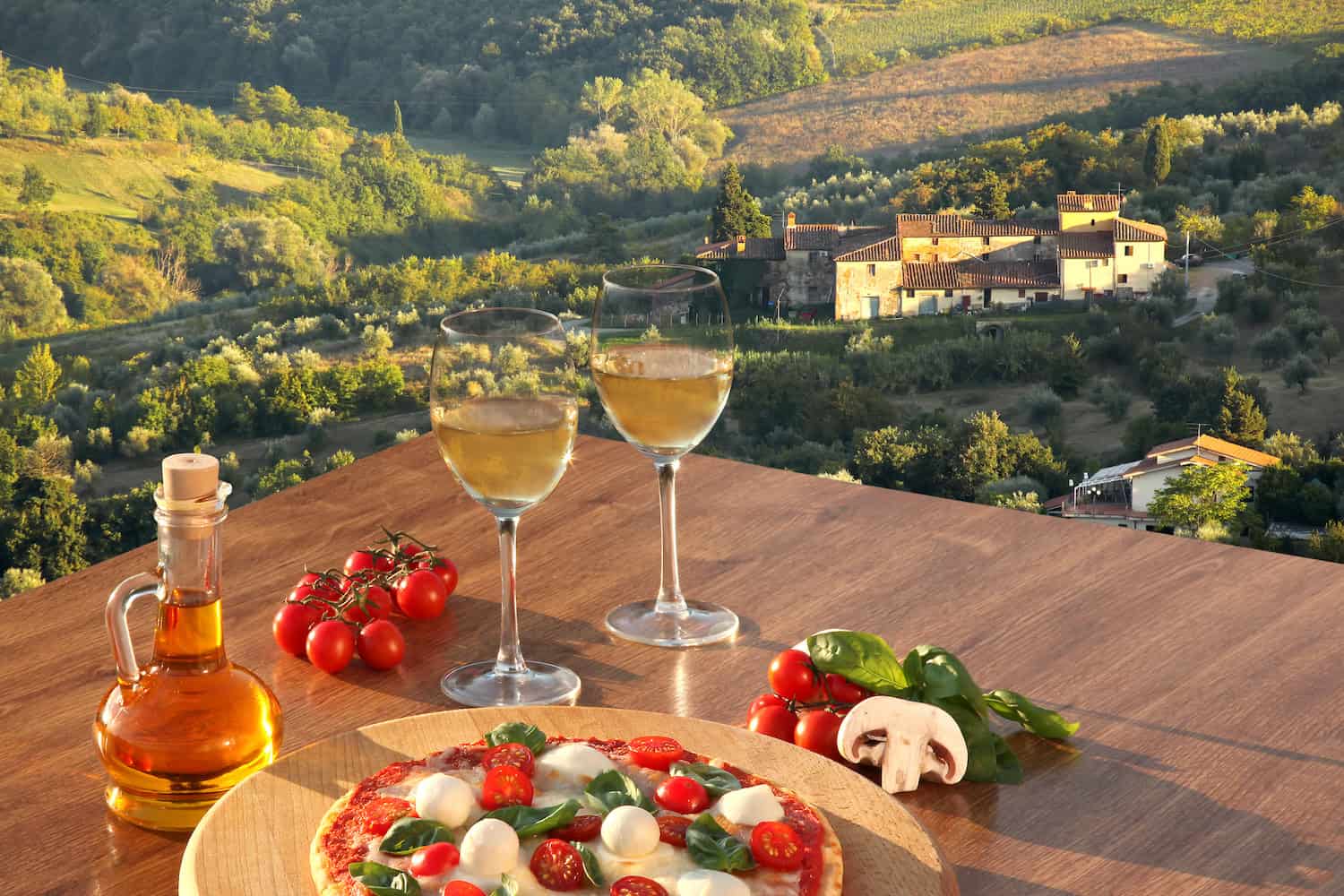 Italian,Pizza,With,Glasses,Of,White,Wine,Against,Tuscan,Vineyards